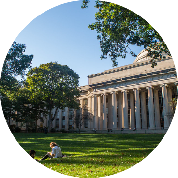 students are sitting on the grass in the yard of university